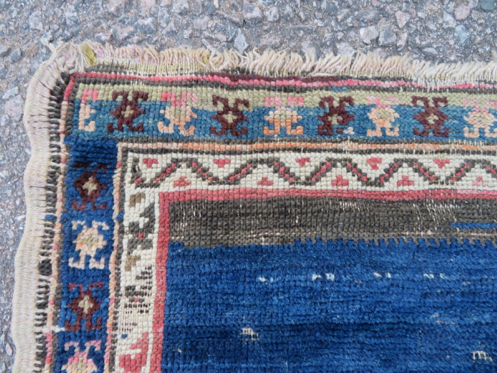 An antique hand-woven Turkish runner rug featuring indigo blue ends and a distressed red and cream geometric central medallion pattern. View IV
