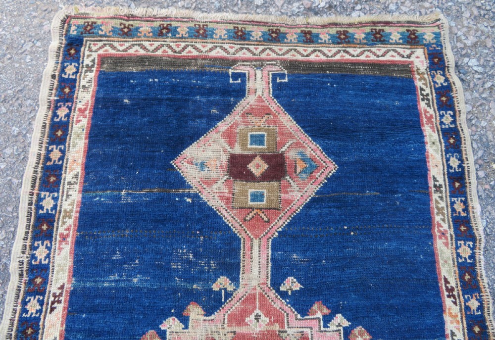 An antique hand-woven Turkish runner rug featuring indigo blue ends and a distressed red and cream geometric central medallion pattern. View V