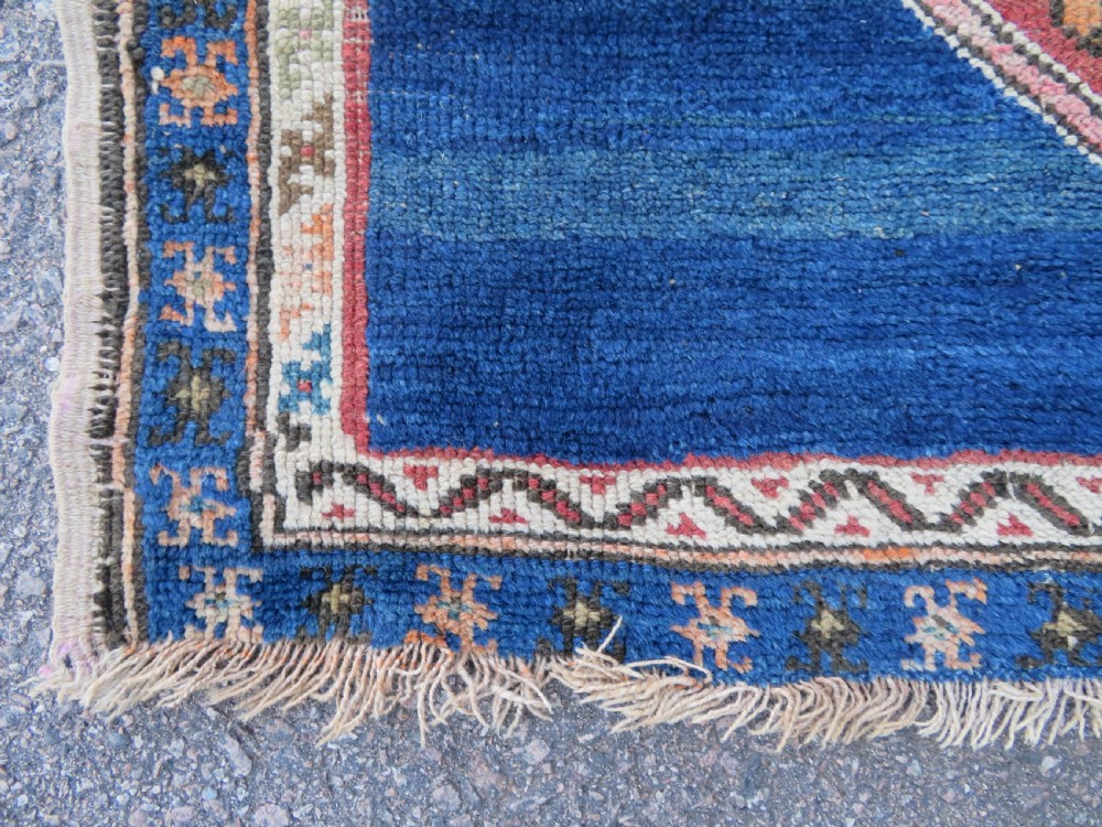 An antique hand-woven Turkish runner rug featuring indigo blue ends and a distressed red and cream geometric central medallion pattern. View XII