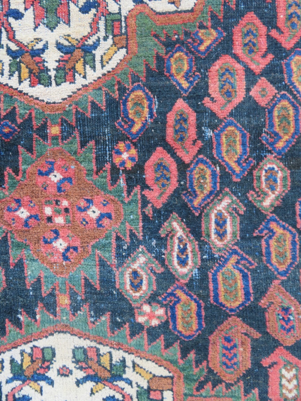A hand-knotted Bakhtiari tribal wool rug with central ivory and blue medallions framed by a dark navy field with repeating boteh patterns and a detailed geometric border. View III