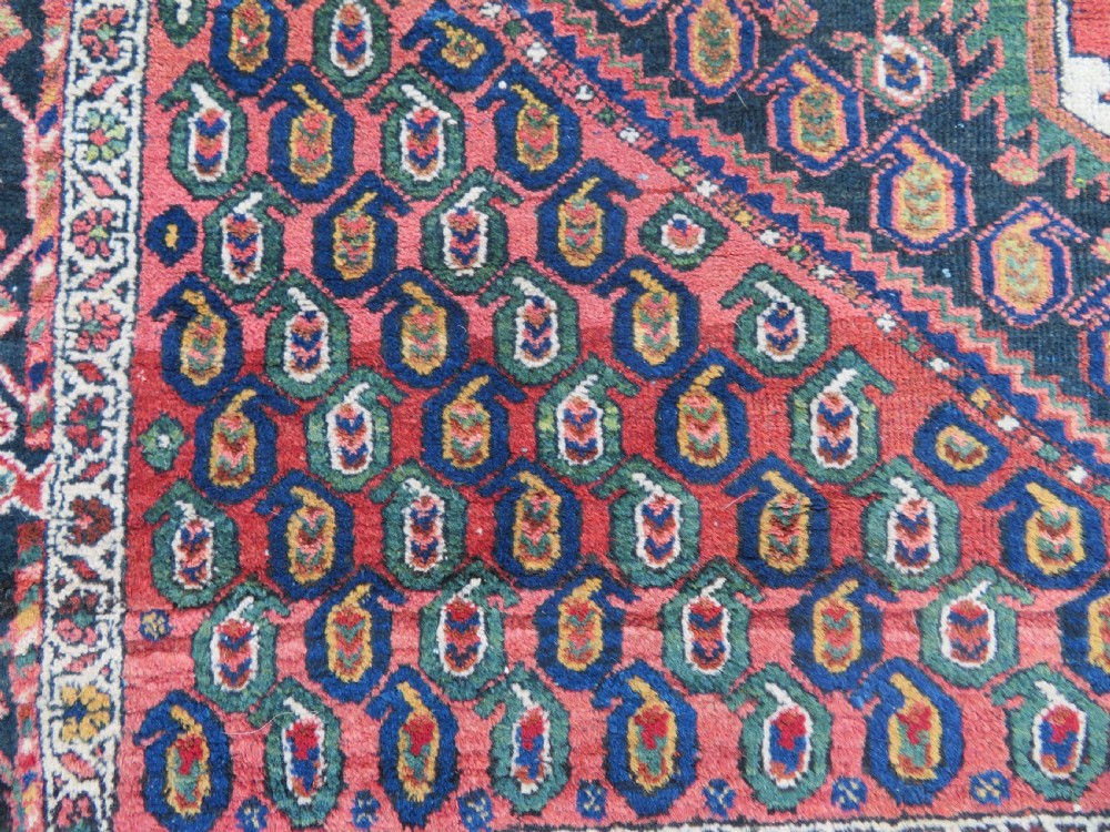 A hand-knotted Bakhtiari tribal wool rug with central ivory and blue medallions framed by a dark navy field with repeating boteh patterns and a detailed geometric border. View V