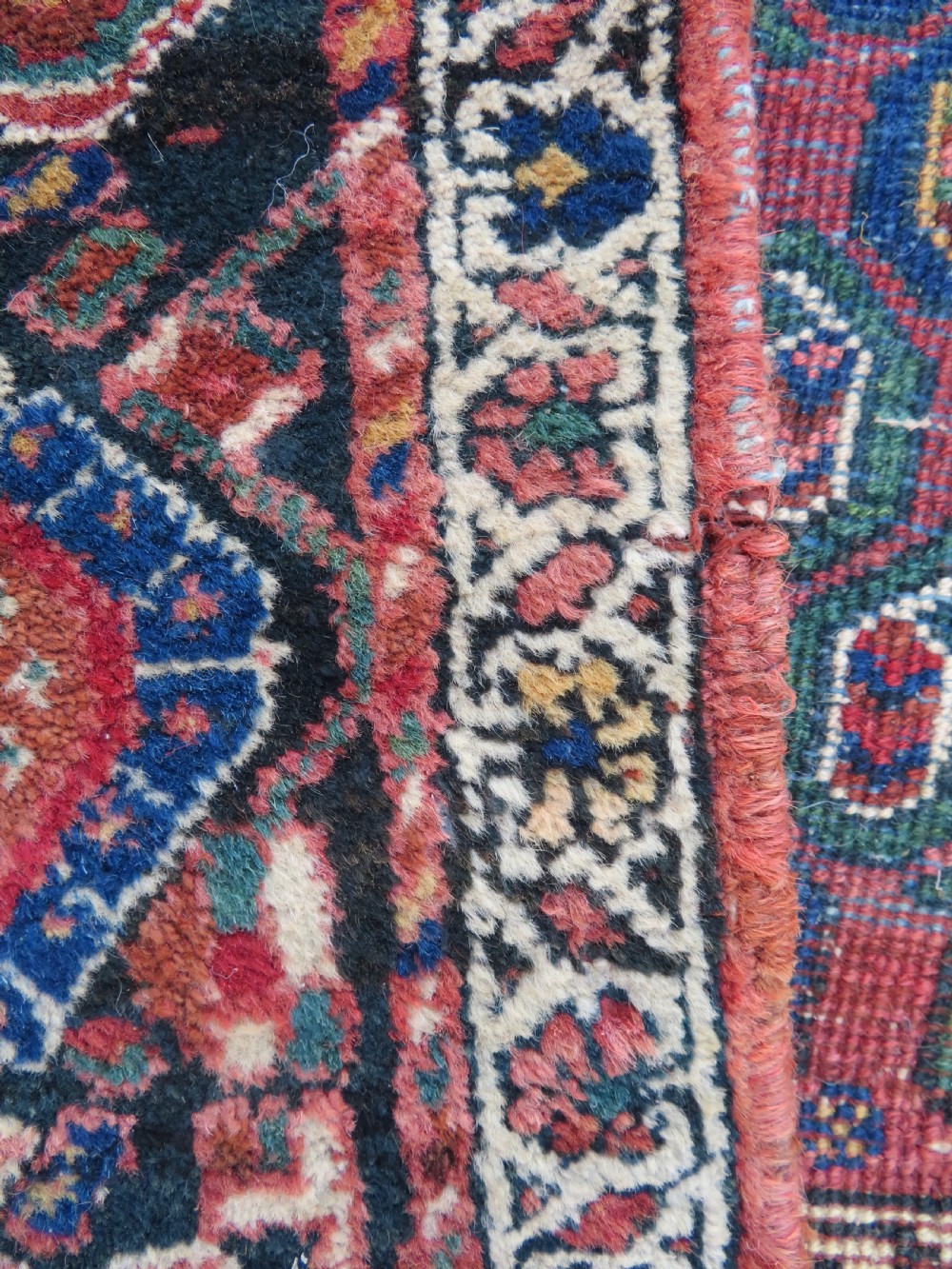A hand-knotted Bakhtiari tribal wool rug with central ivory and blue medallions framed by a dark navy field with repeating boteh patterns and a detailed geometric border. View VII