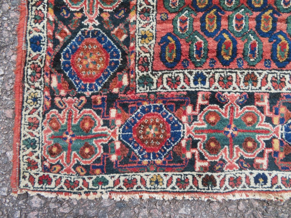 A hand-knotted Bakhtiari tribal wool rug with central ivory and blue medallions framed by a dark navy field with repeating boteh patterns and a detailed geometric border. View X