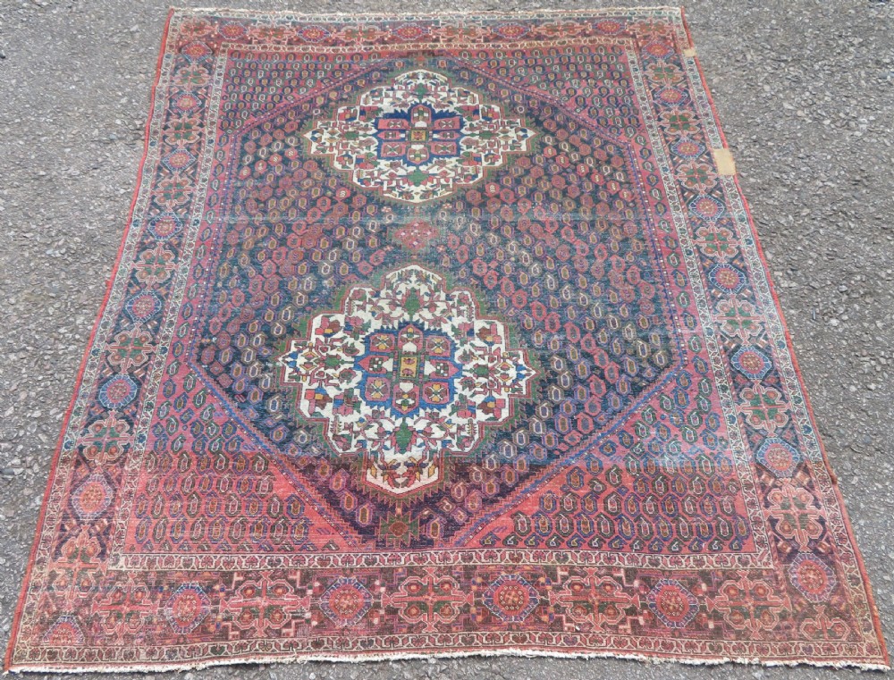 A hand-knotted Bakhtiari tribal wool rug with central ivory and blue medallions framed by a dark navy field with repeating boteh patterns and a detailed geometric border. View XII