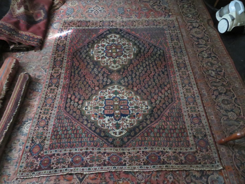 A hand-knotted Bakhtiari tribal wool rug with central ivory and blue medallions framed by a dark navy field with repeating boteh patterns and a detailed geometric border. View XVII