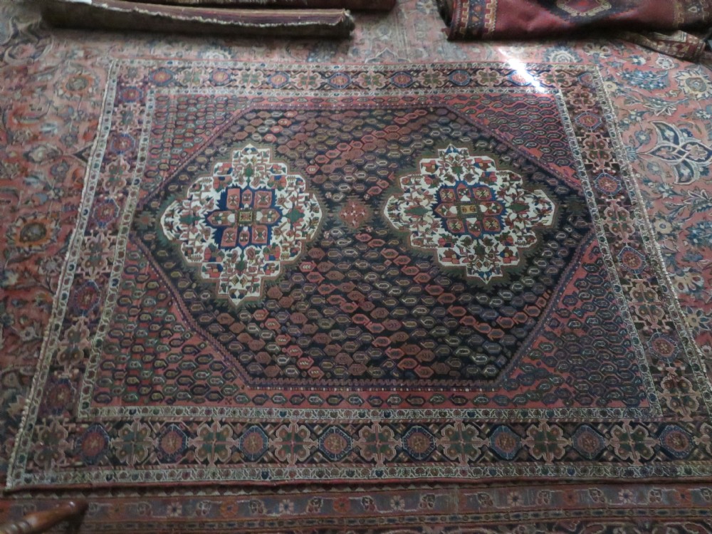 A hand-knotted Bakhtiari tribal wool rug with central ivory and blue medallions framed by a dark navy field with repeating boteh patterns and a detailed geometric border. View XVIII