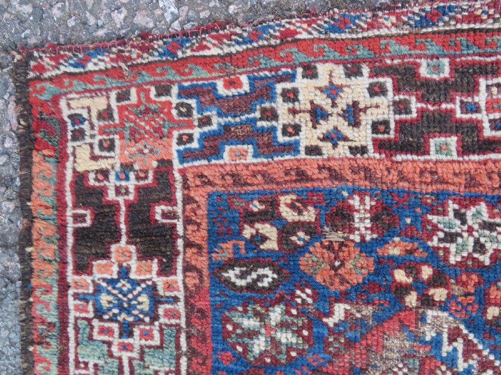 An antique Khamseh hand-knotted wool rug featuring three stacked geometric diamond medallions on an indigo blue field surrounded by intricate patterned borders. View V