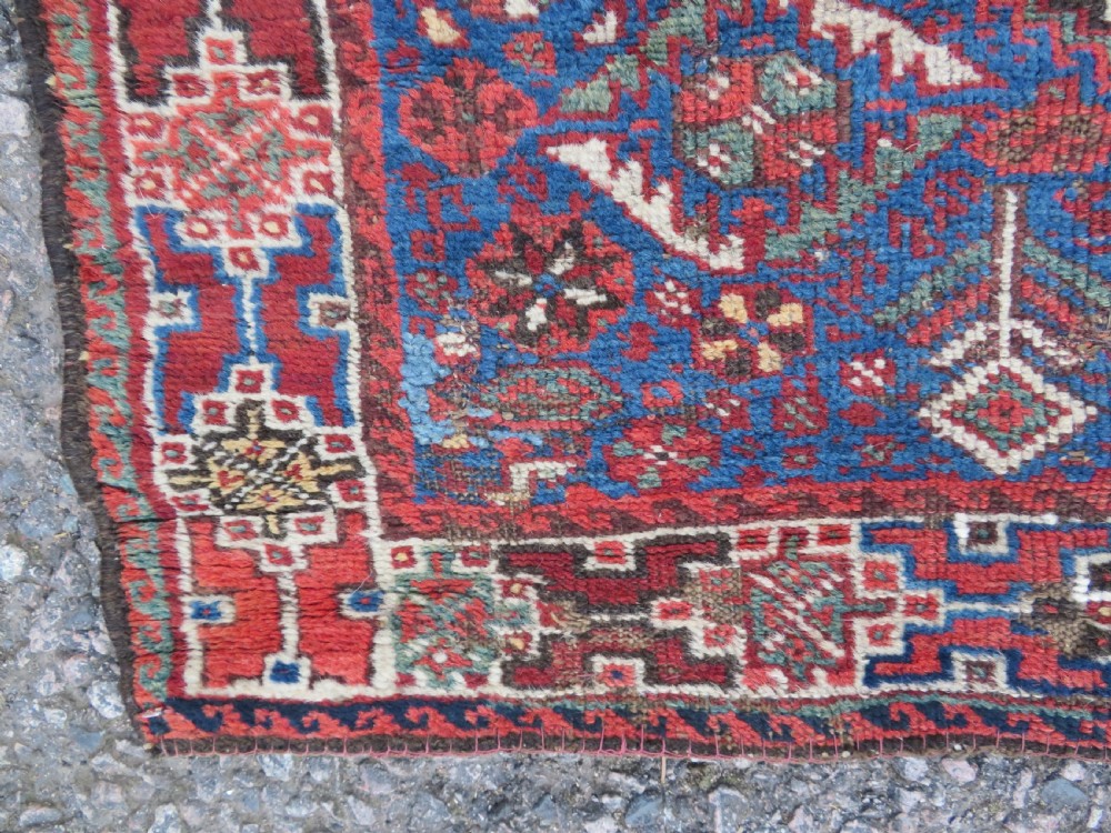 An antique Khamseh hand-knotted wool rug featuring three stacked geometric diamond medallions on an indigo blue field surrounded by intricate patterned borders. View VIII