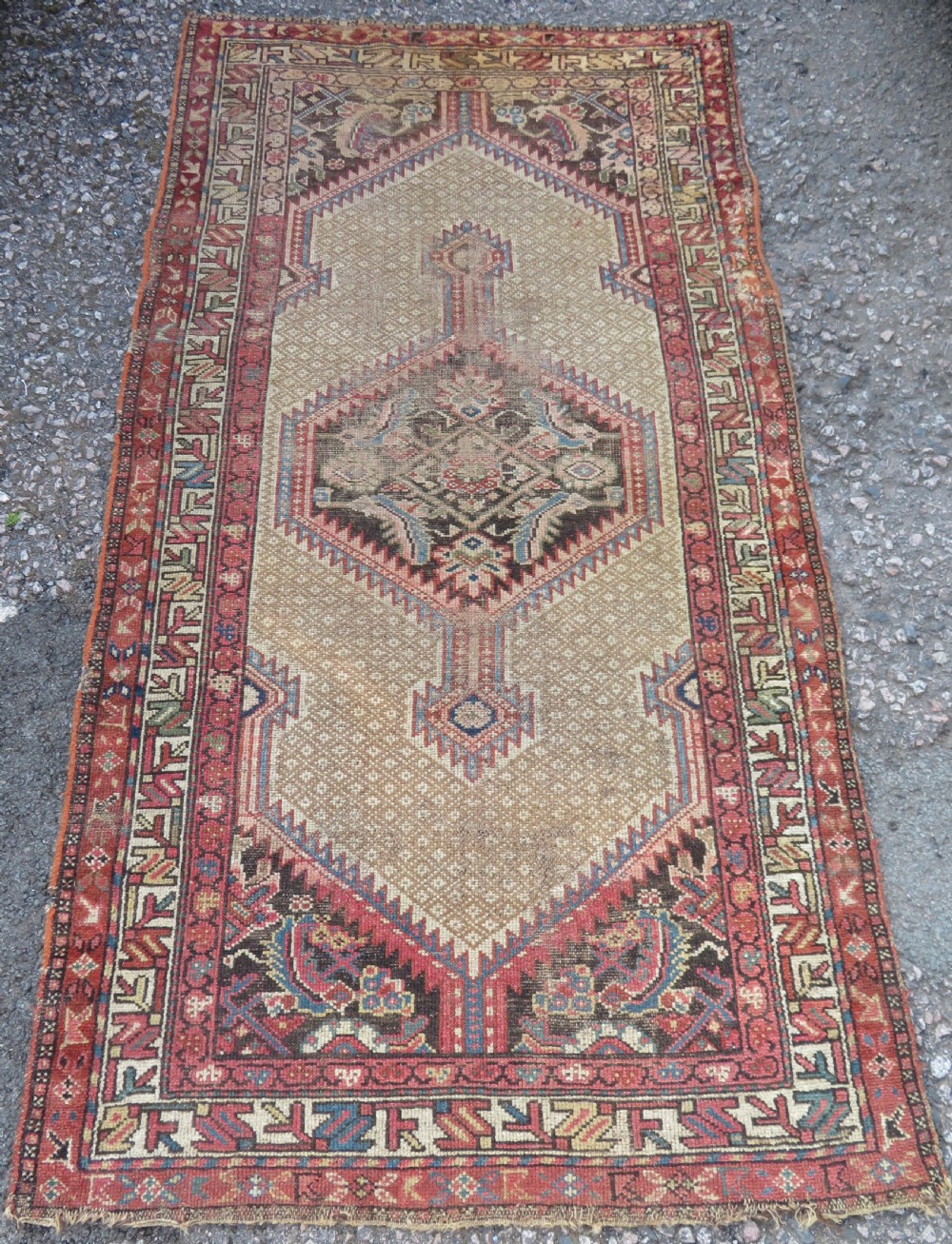 An antique hand-knotted Sarab rug with a geometric central medallion, camel hair field, and distressed terracotta borders.
