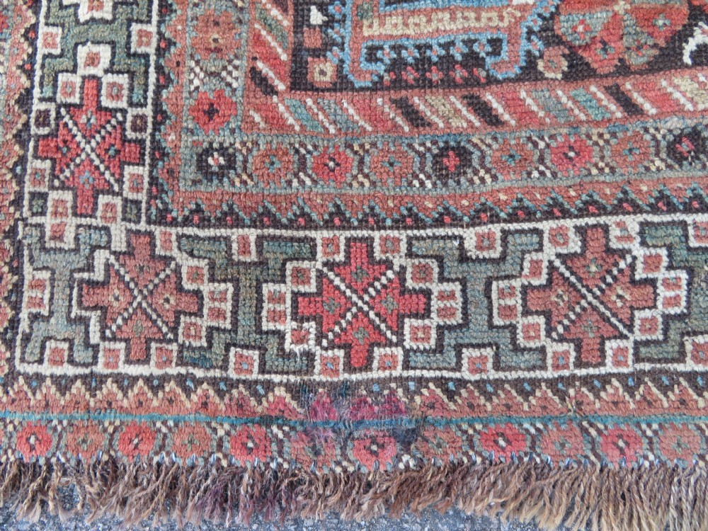 A rectangular hand-knotted antique Khamseh wool rug featuring geometric diamond medallions and intricate border patterns in terracotta, dark brown, and cream. View XIV