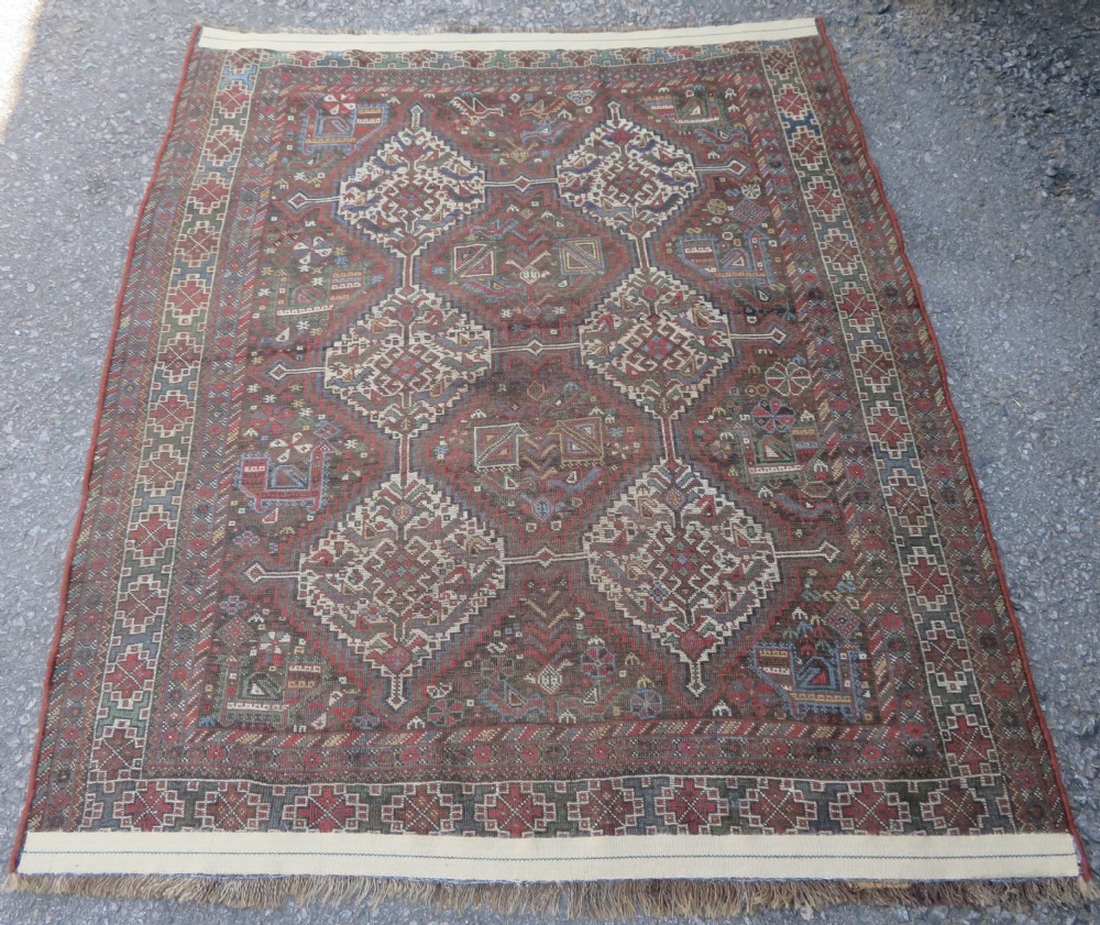A rectangular hand-knotted antique Khamseh wool rug featuring geometric diamond medallions and intricate border patterns in terracotta, dark brown, and cream. View XVII