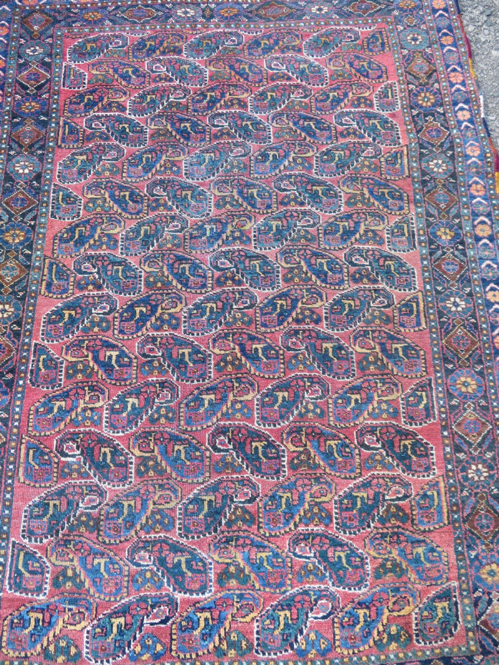 An antique hand-knotted wool Afshar tribal rug featuring a repeating boteh pattern on a terracotta field with geometric blue and cream borders. View II