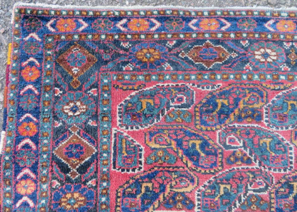 An antique hand-knotted wool Afshar tribal rug featuring a repeating boteh pattern on a terracotta field with geometric blue and cream borders. View V