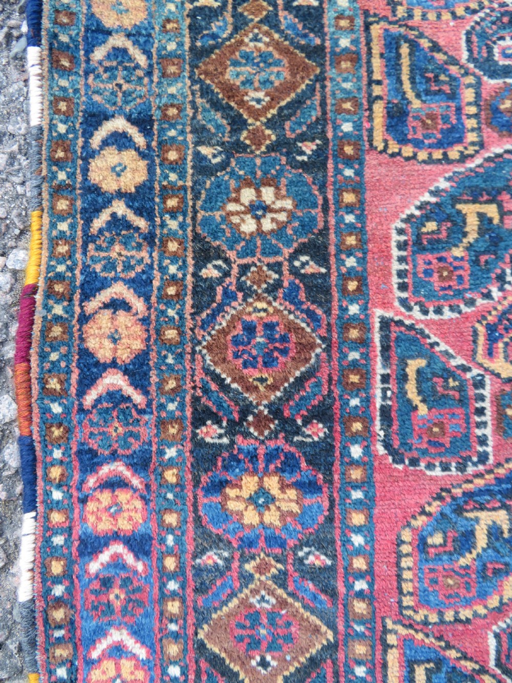 An antique hand-knotted wool Afshar tribal rug featuring a repeating boteh pattern on a terracotta field with geometric blue and cream borders. View X