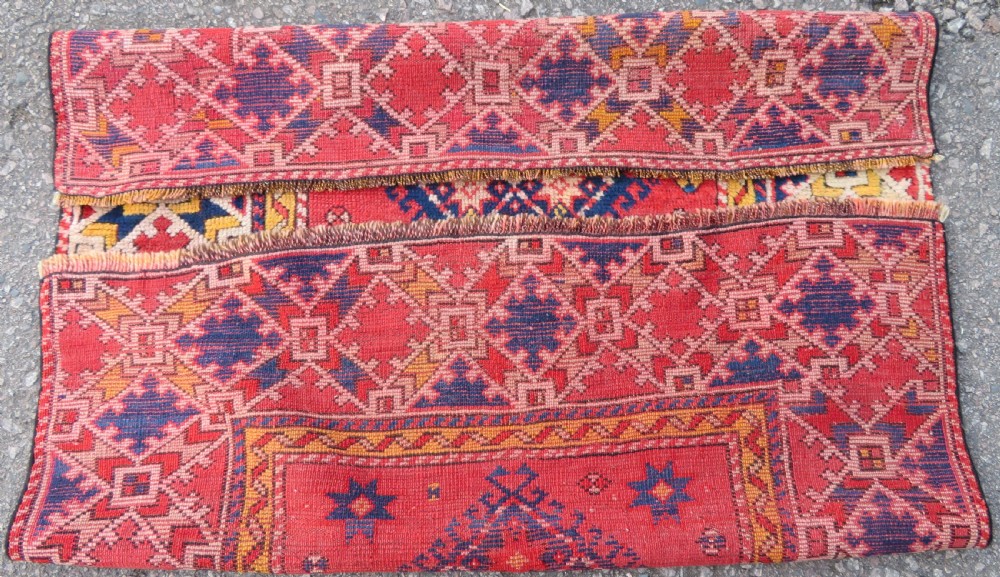 An antique hand-knotted wool rug featuring geometric diamond medallions in red, dark blue, yellow, and cream with a detailed border pattern. View XI