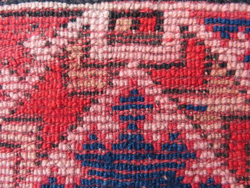 An antique hand-knotted wool rug featuring geometric diamond medallions in red, dark blue, yellow, and cream with a detailed border pattern. View XIII