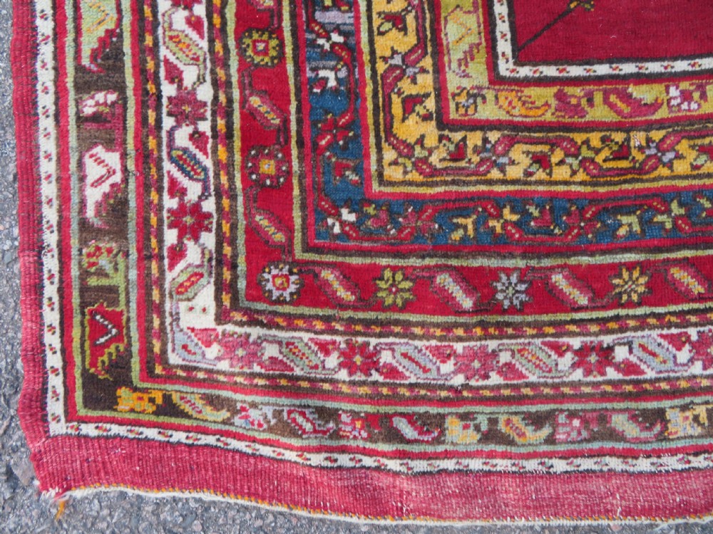 An antique hand-knotted Turkish Kirsehir prayer rug featuring a central red mihrab arch framed by a yellow spandrel and multi-tiered geometric borders. View IX