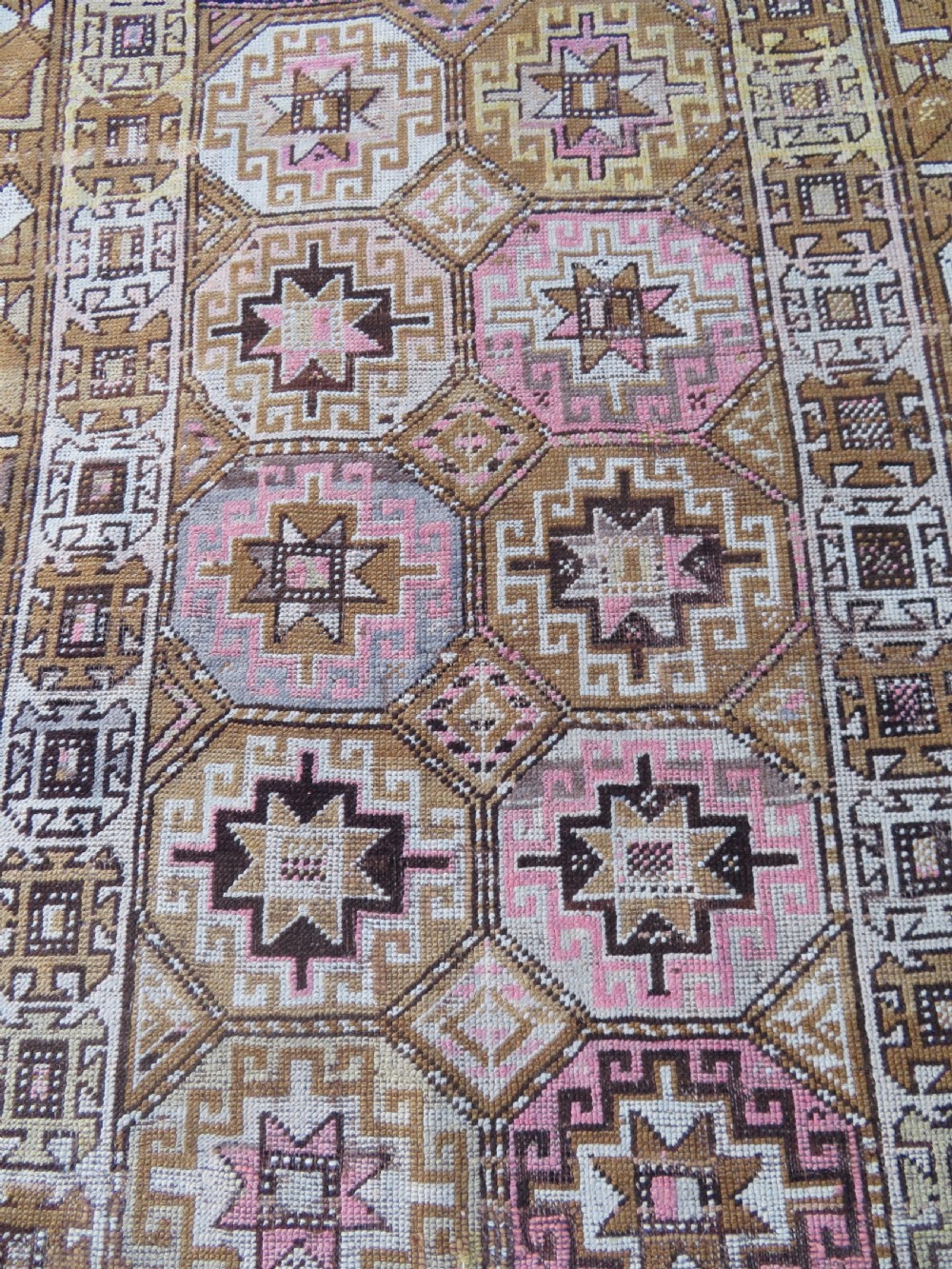 An antique Kurdish hand-knotted wool rug runner featuring repeated geometric octagonal medallions in shades of pink, tan, cream, and dark brown. View IV