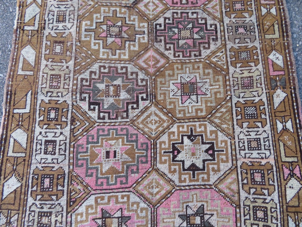 An antique Kurdish hand-knotted wool rug runner featuring repeated geometric octagonal medallions in shades of pink, tan, cream, and dark brown. View V