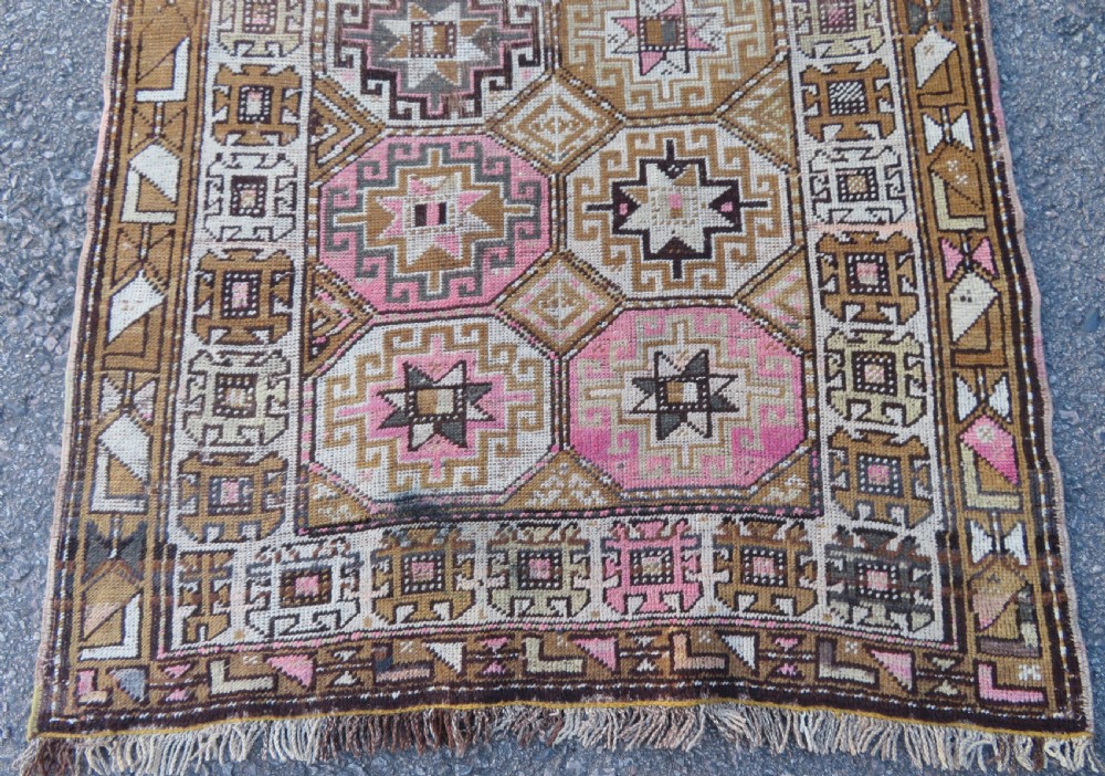 An antique Kurdish hand-knotted wool rug runner featuring repeated geometric octagonal medallions in shades of pink, tan, cream, and dark brown. View VI