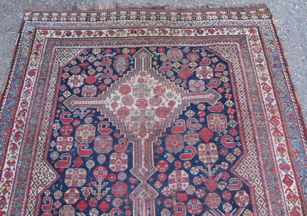 An antique hand-knotted Persian Khamseh carpet featuring three central diamond pole medallions on a dark navy blue field filled with geometric tribal bird and flower motifs surrounded by intricate decorative borders. View III