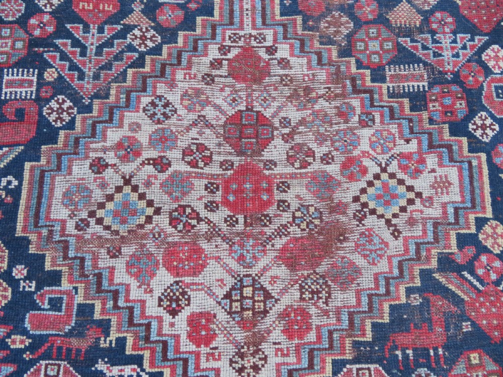 An antique hand-knotted Persian Khamseh carpet featuring three central diamond pole medallions on a dark navy blue field filled with geometric tribal bird and flower motifs surrounded by intricate decorative borders. View VII