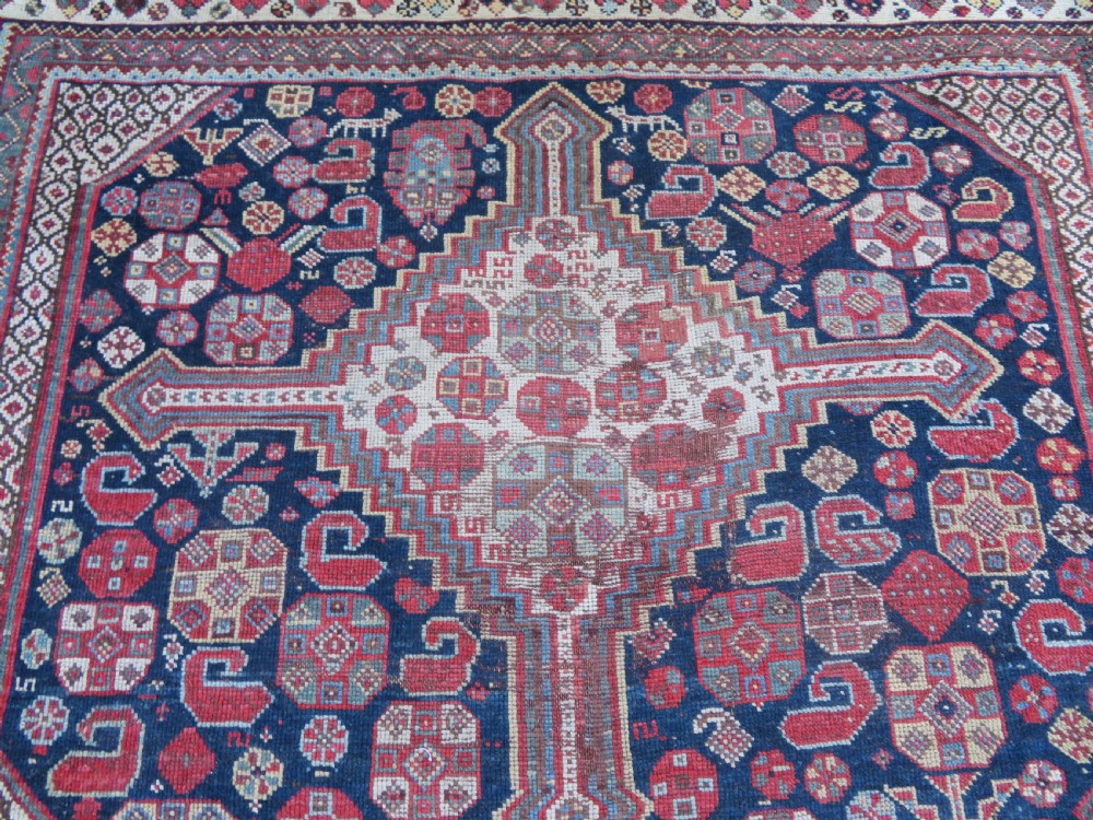An antique hand-knotted Persian Khamseh carpet featuring three central diamond pole medallions on a dark navy blue field filled with geometric tribal bird and flower motifs surrounded by intricate decorative borders. View VIII