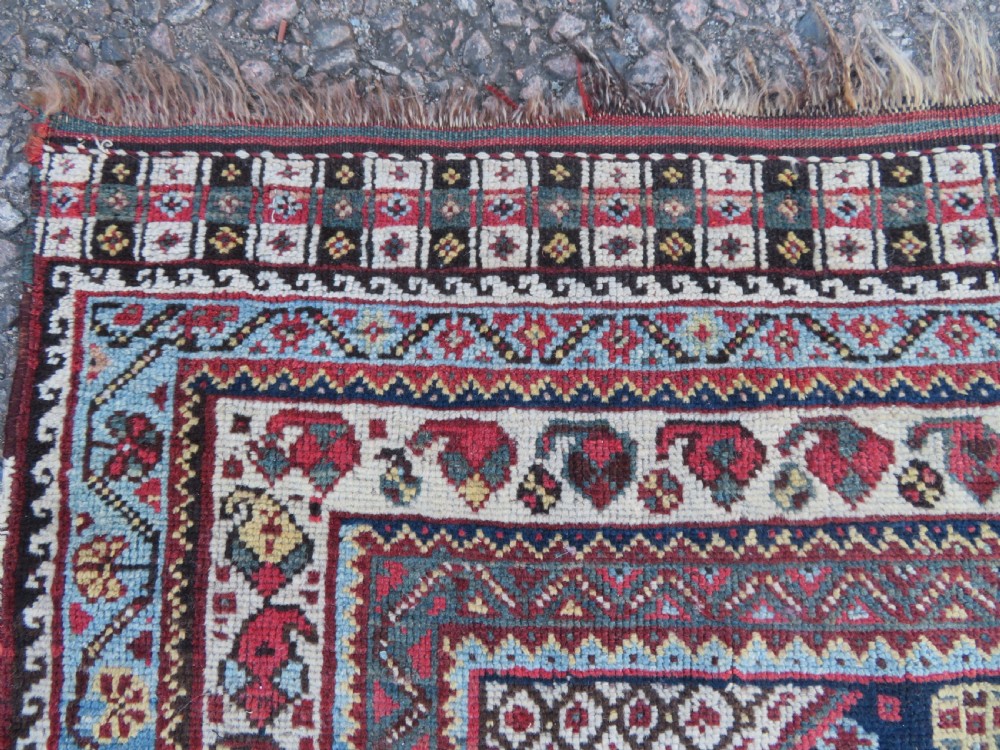 An antique hand-knotted Persian Khamseh carpet featuring three central diamond pole medallions on a dark navy blue field filled with geometric tribal bird and flower motifs surrounded by intricate decorative borders. View IX