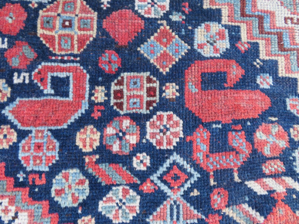 An antique hand-knotted Persian Khamseh carpet featuring three central diamond pole medallions on a dark navy blue field filled with geometric tribal bird and flower motifs surrounded by intricate decorative borders. View XIII
