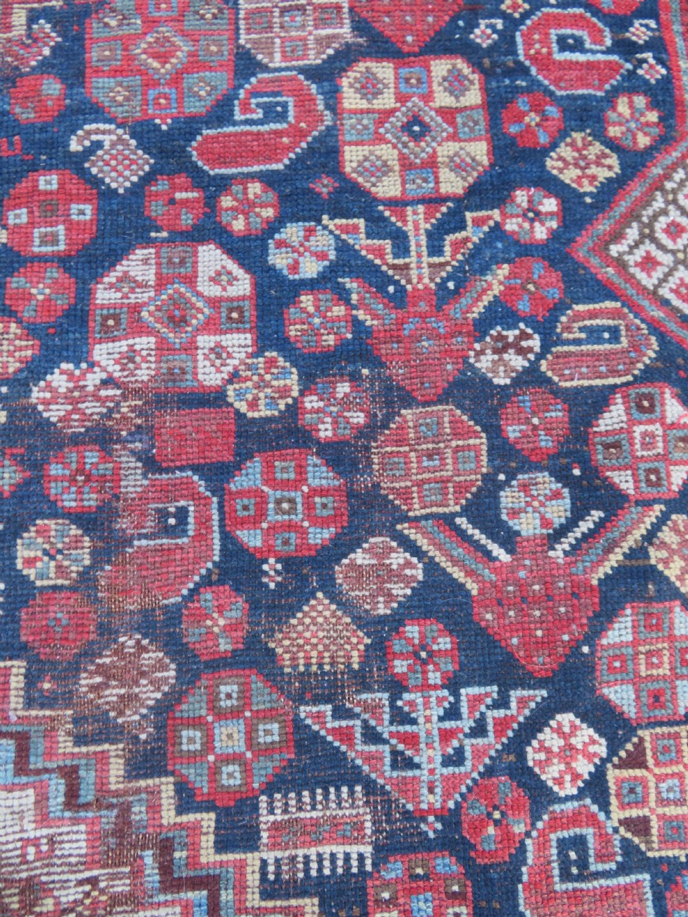 An antique hand-knotted Persian Khamseh carpet featuring three central diamond pole medallions on a dark navy blue field filled with geometric tribal bird and flower motifs surrounded by intricate decorative borders. View XVII