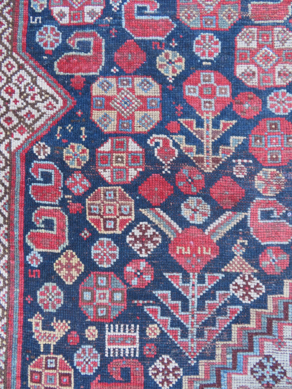 An antique hand-knotted Persian Khamseh carpet featuring three central diamond pole medallions on a dark navy blue field filled with geometric tribal bird and flower motifs surrounded by intricate decorative borders. View XVIII