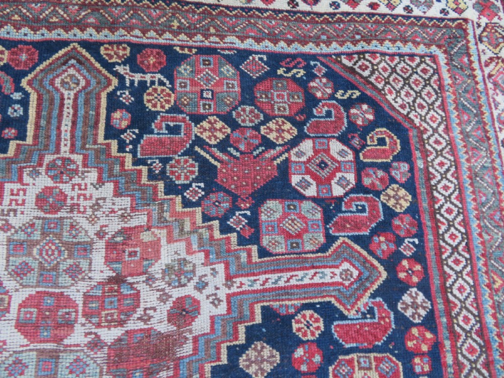 An antique hand-knotted Persian Khamseh carpet featuring three central diamond pole medallions on a dark navy blue field filled with geometric tribal bird and flower motifs surrounded by intricate decorative borders. View XXI