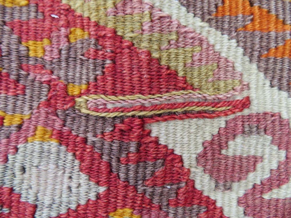 A flatwoven Anatolian kilim grain sack featuring geometric diamond motifs in red, orange, cream, and brown wool with corner tassels. View IV