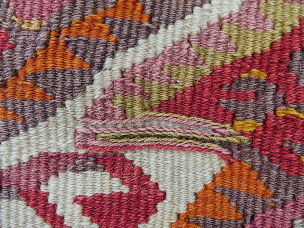 A flatwoven Anatolian kilim grain sack featuring geometric diamond motifs in red, orange, cream, and brown wool with corner tassels. View V