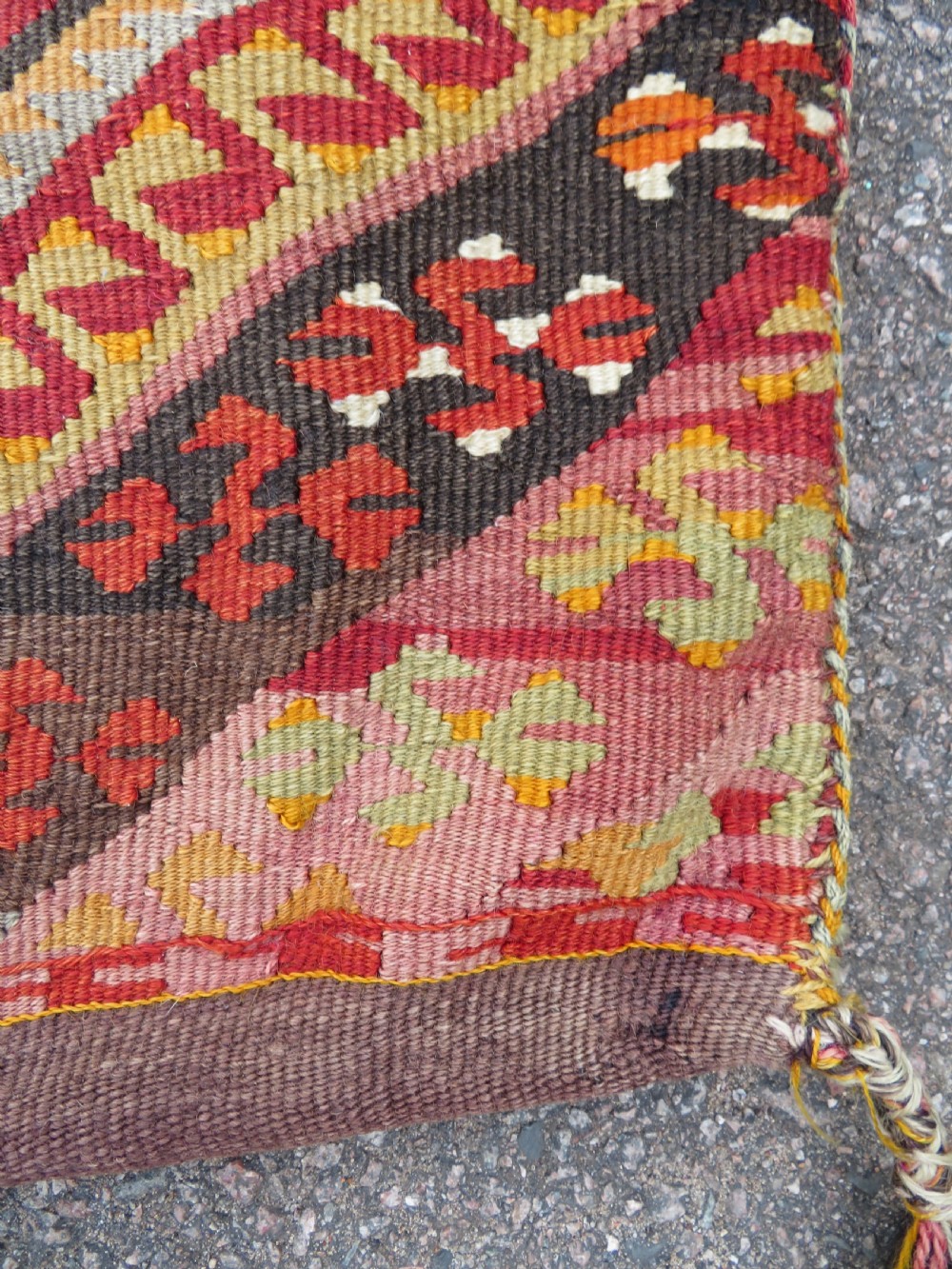 A flatwoven Anatolian kilim grain sack featuring geometric diamond motifs in red, orange, cream, and brown wool with corner tassels. View VI
