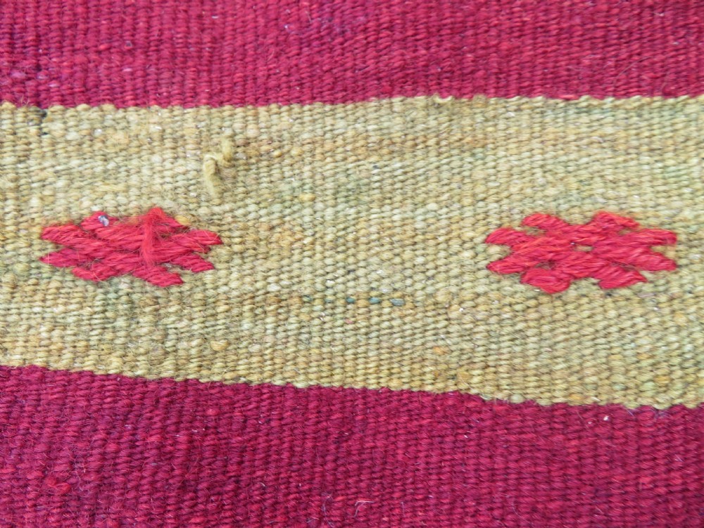 A flatwoven Anatolian kilim grain sack featuring geometric diamond motifs in red, orange, cream, and brown wool with corner tassels. View X