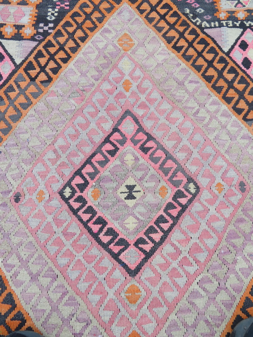 An antique flatwoven Turkish kilim rug featuring central diamond medallions and geometric borders in shades of pink, terracotta, cream, and dark brown. View IV