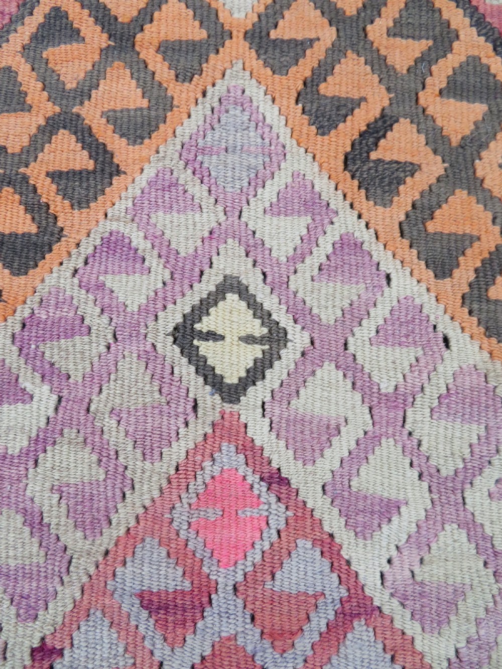 An antique flatwoven Turkish kilim rug featuring central diamond medallions and geometric borders in shades of pink, terracotta, cream, and dark brown. View XI