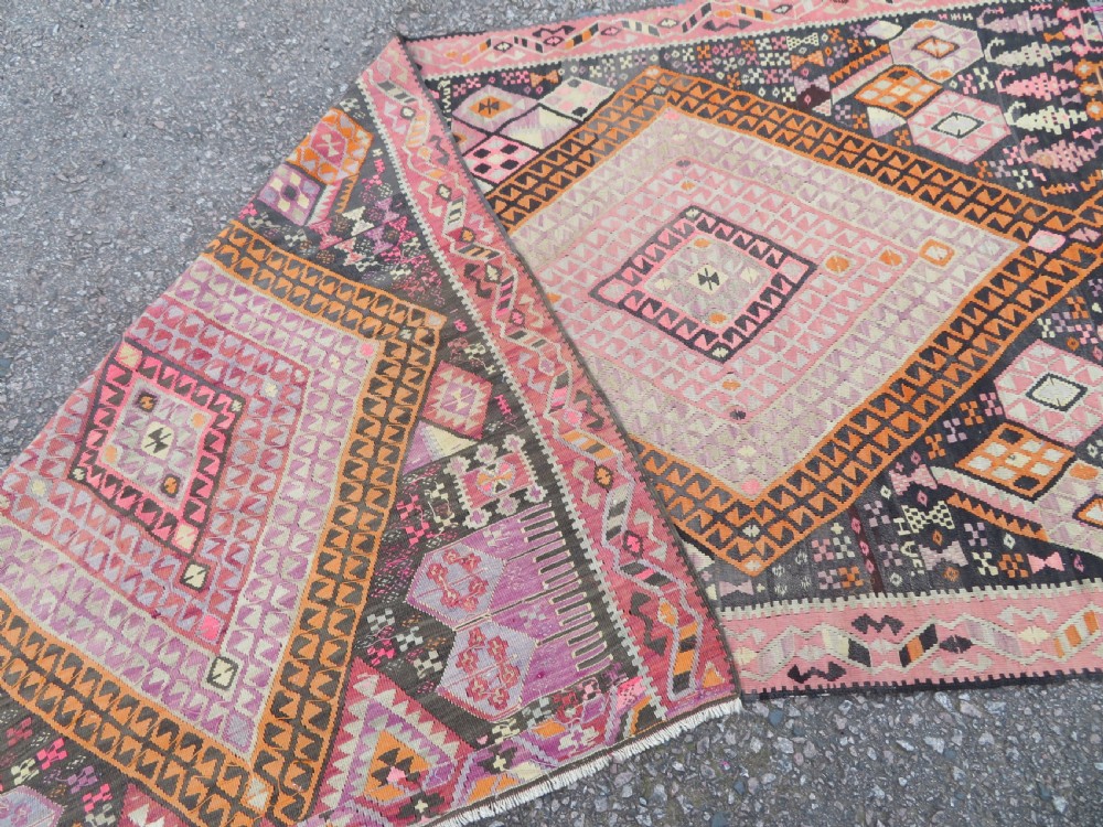 An antique flatwoven Turkish kilim rug featuring central diamond medallions and geometric borders in shades of pink, terracotta, cream, and dark brown. View XIII