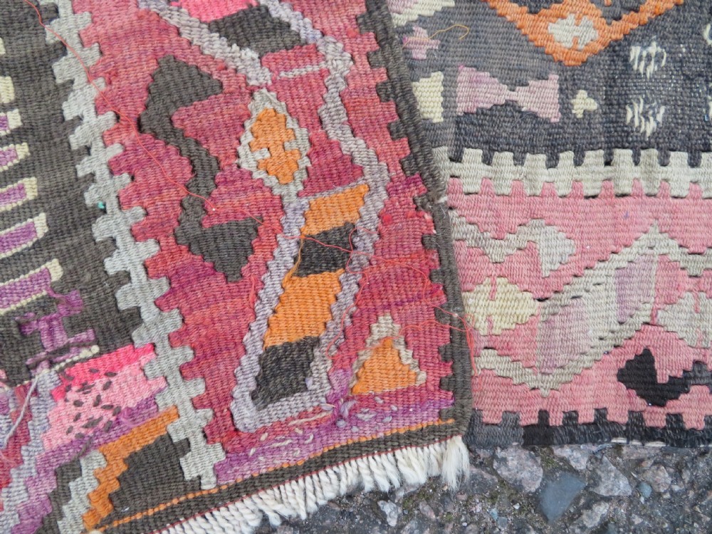 An antique flatwoven Turkish kilim rug featuring central diamond medallions and geometric borders in shades of pink, terracotta, cream, and dark brown. View XIV