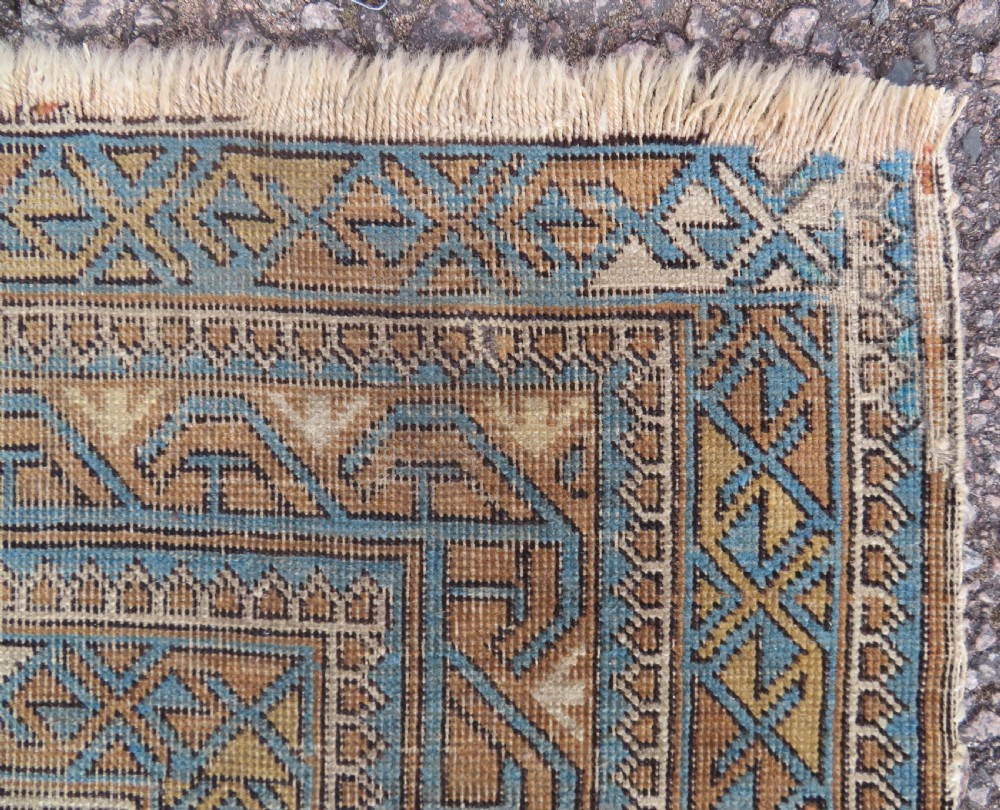 An antique hand-knotted Caucasian Kuba Seichur wool rug featuring a geometric white ground field surrounded by multi-layered patterned borders in blue, terracotta, and ochre. View VII
