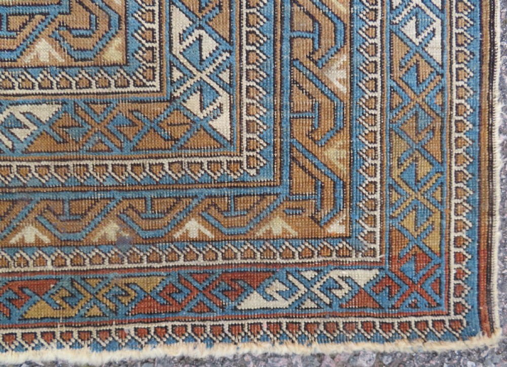 An antique hand-knotted Caucasian Kuba Seichur wool rug featuring a geometric white ground field surrounded by multi-layered patterned borders in blue, terracotta, and ochre. View XI