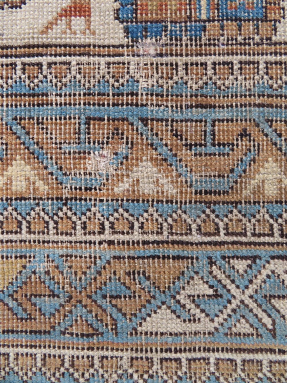 An antique hand-knotted Caucasian Kuba Seichur wool rug featuring a geometric white ground field surrounded by multi-layered patterned borders in blue, terracotta, and ochre. View XII