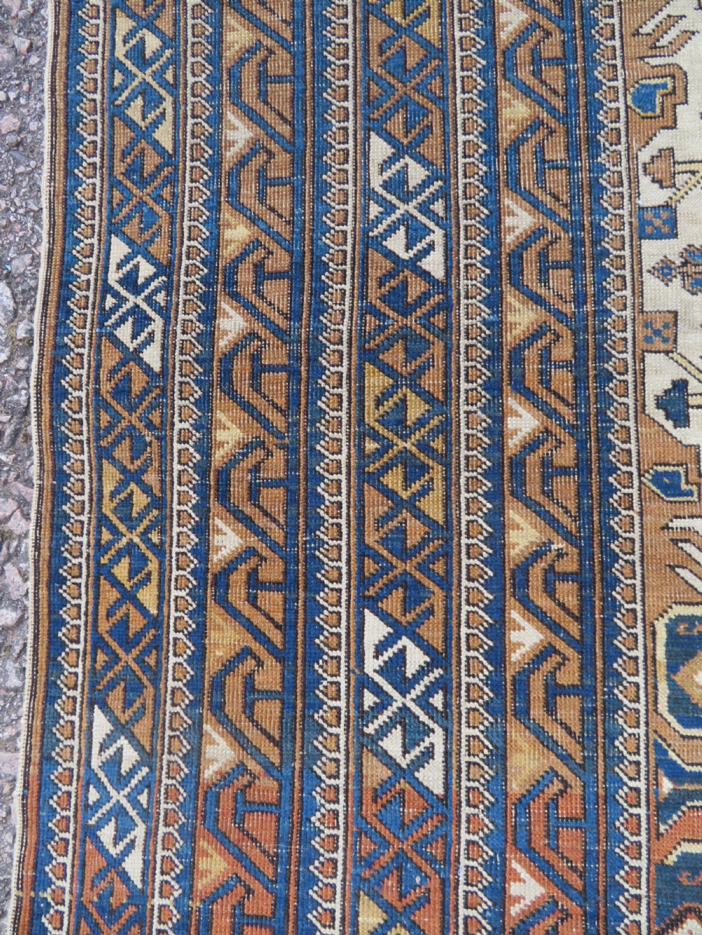 An antique hand-knotted Caucasian Kuba Seichur wool rug featuring a geometric white ground field surrounded by multi-layered patterned borders in blue, terracotta, and ochre. View XIII