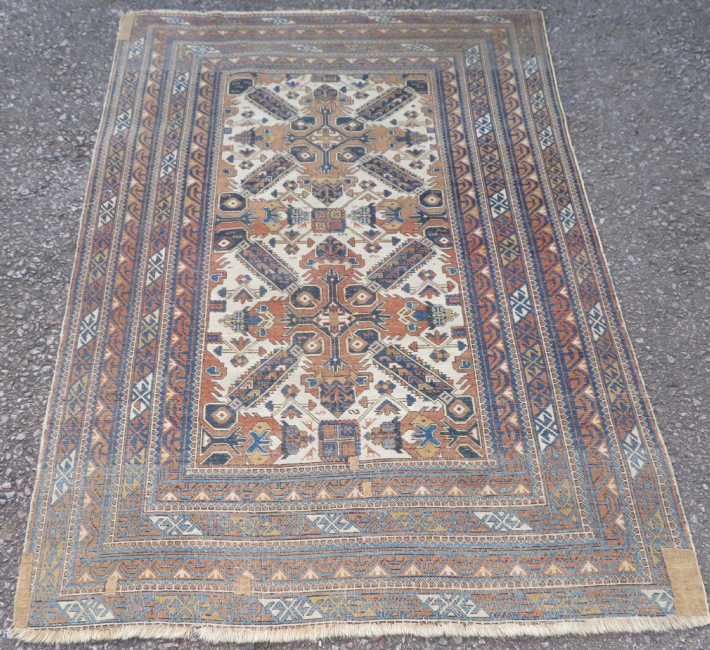 An antique hand-knotted Caucasian Kuba Seichur wool rug featuring a geometric white ground field surrounded by multi-layered patterned borders in blue, terracotta, and ochre. View XIV