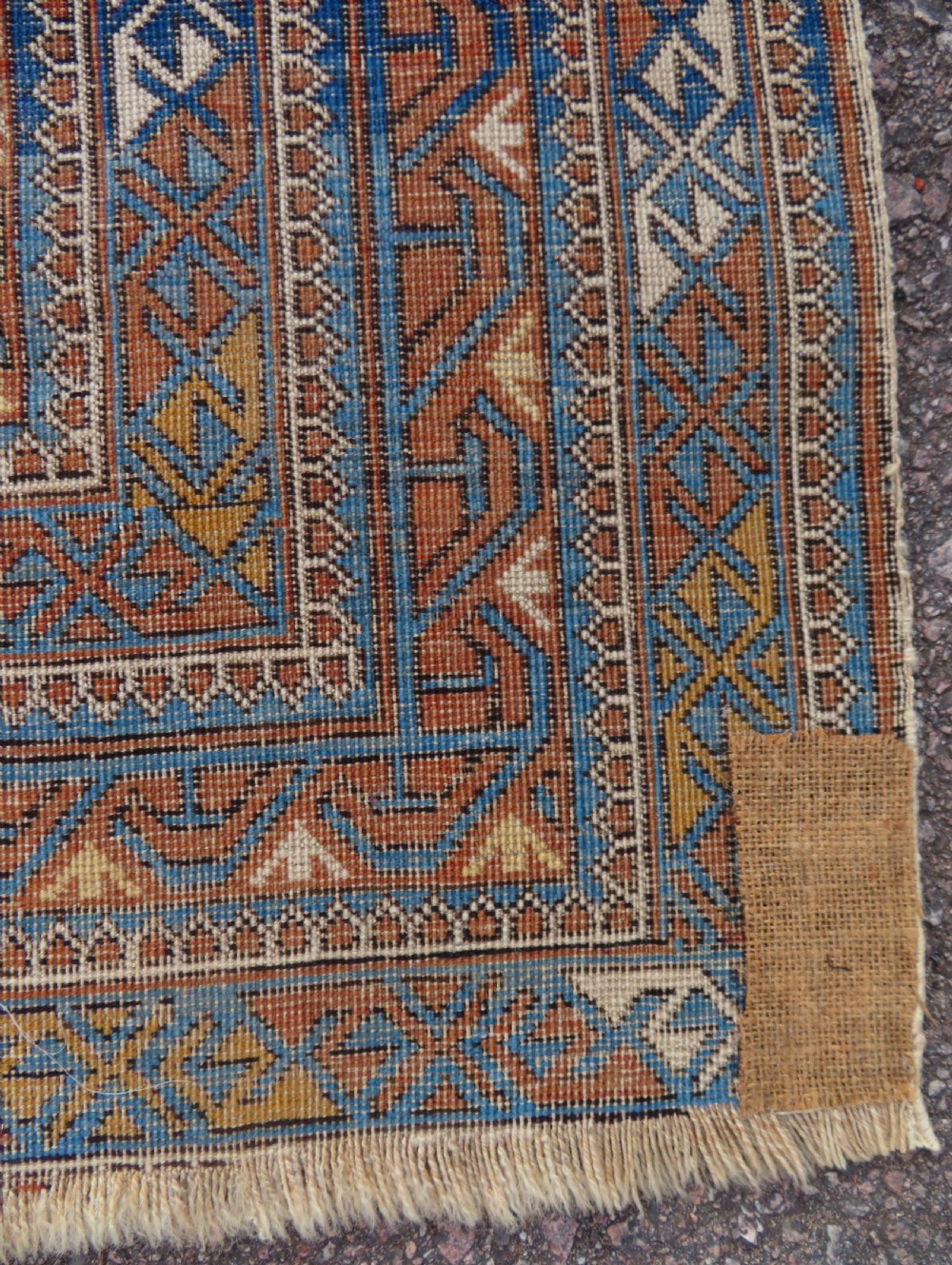 An antique hand-knotted Caucasian Kuba Seichur wool rug featuring a geometric white ground field surrounded by multi-layered patterned borders in blue, terracotta, and ochre. View XVI
