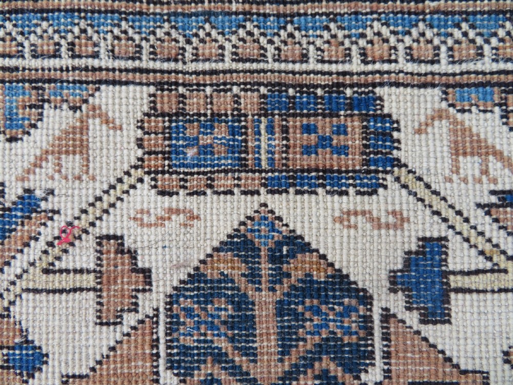 An antique hand-knotted Caucasian Kuba Seichur wool rug featuring a geometric white ground field surrounded by multi-layered patterned borders in blue, terracotta, and ochre. View XVIII