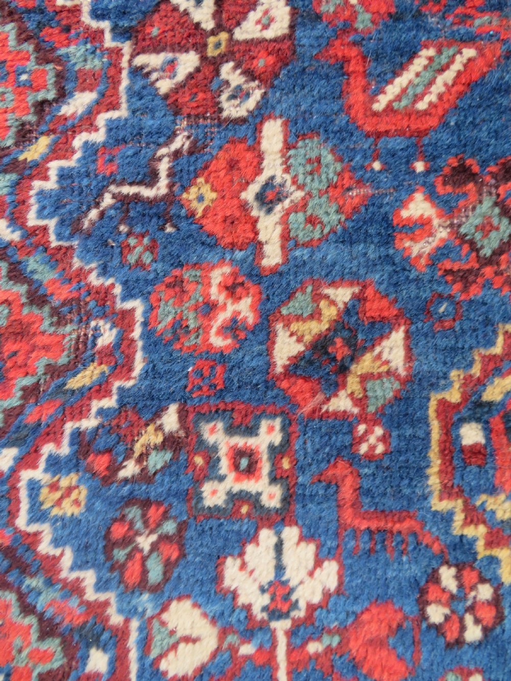 An antique South Persian Khamseh rug featuring three diamond-shaped central medallions and geometric bird motifs in shades of red, navy blue, and cream. View IV