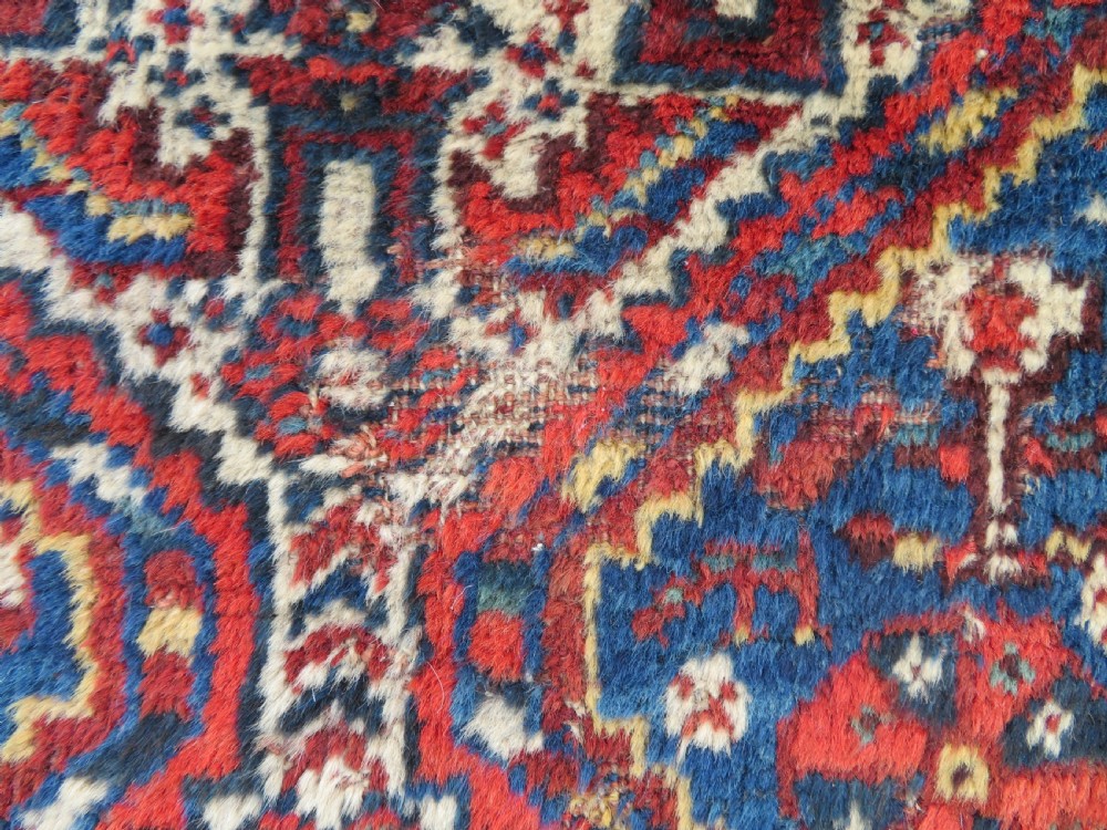 An antique South Persian Khamseh rug featuring three diamond-shaped central medallions and geometric bird motifs in shades of red, navy blue, and cream. View VI