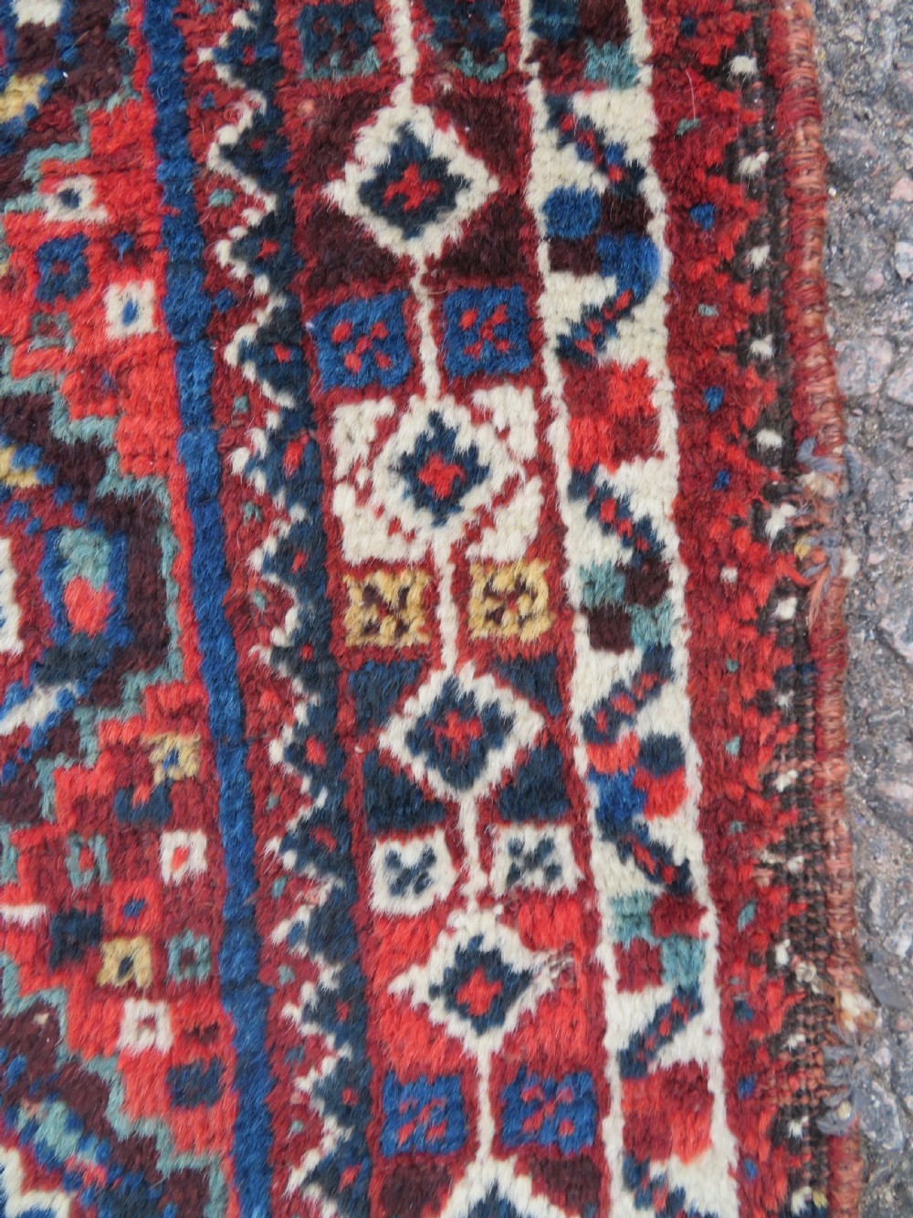 An antique South Persian Khamseh rug featuring three diamond-shaped central medallions and geometric bird motifs in shades of red, navy blue, and cream. View IX